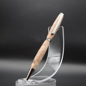 Op de afbeelding: Een houten pen met een zilveren metalen rand en een bruin houtnerfpatroon. De pen wordt getoond op een transparante kunststof standaard.