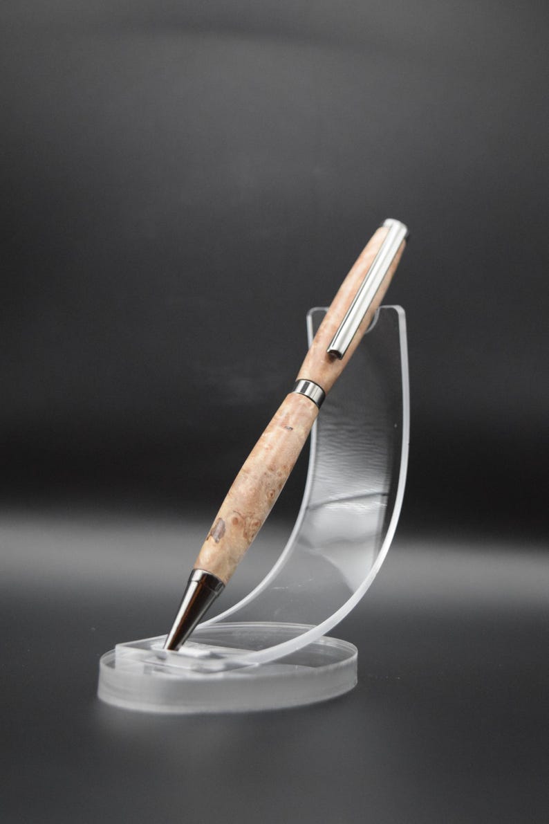 Op de afbeelding: Een houten pen met een zilveren metalen rand en een bruin houtnerfpatroon. De pen wordt getoond op een transparante kunststof standaard.