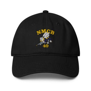 May include: Black baseball cap with embroidered design. The design features the letters "NMCB" in gold, along with a cartoon image of a bee and the number "40". The cap has a curved brim and an adjustable strap.