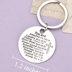 May include: Silver keychain with a round charm that reads "You are Amazing" and includes a list of positive affirmations and bible verses. The charm is 1.2 inches in diameter.