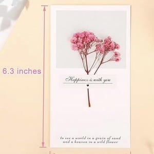 May include: A white greeting card with a dried pink flower arrangement and the text "Happiness is with you". The card measures 6.3 inches by 3.5 inches.