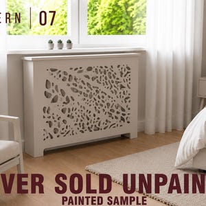May include: A white radiator cover featuring a decorative cutout pattern labeled PATTERN 07. The rectangular unit has a flat top surface and a front panel with organic, leaf-like perforations. The text COVER SOLD UNPAINTED PAINTED SAMPLE is visible.