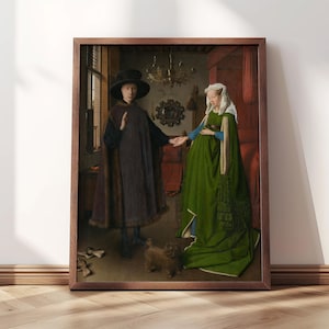 Puede incluir: Una impresi&oacute;n enmarcada de una pintura de estilo renacentista. La obra de arte representa a dos figuras con ropa de &eacute;poca, un hombre con una capa y sombrero oscuros, y una mujer con un vestido verde. Un perro peque&ntilde;o est&aacute; a sus pies. La impresi&oacute;n se exhibe en una pared blanca.