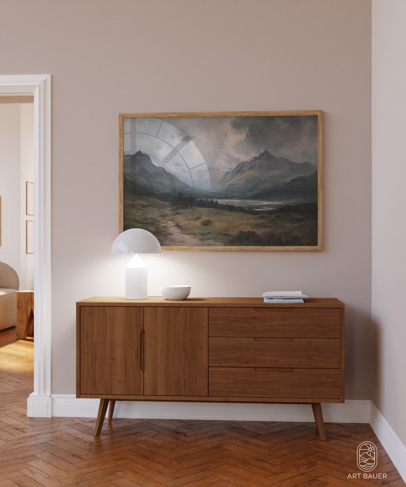 Pu&ograve; includere: Un credenza in legno con due ante e tre cassetti. La credenza &egrave; di colore marrone chiaro e ha un design moderno. Una lampada bianca e una ciotola bianca sono sopra la credenza. Un dipinto di paesaggio incorniciato &egrave; appeso al muro sopra la credenza.