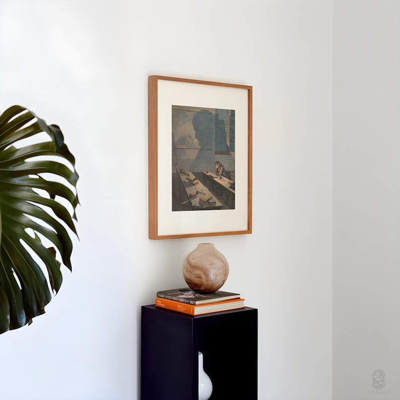 May include: A framed print of a vintage illustration depicting a person sitting at a desk in a room with a window. The print is on a white wall above a black pedestal with a wooden vase and two books.