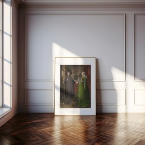 Puede incluir: Una obra de arte enmarcada que representa a dos figuras con vestimenta hist&oacute;rica. Una figura lleva una capa y un sombrero oscuros, la otra un vestido verde. La obra de arte se exhibe en una habitaci&oacute;n con paredes blancas, una ventana y un suelo de madera.