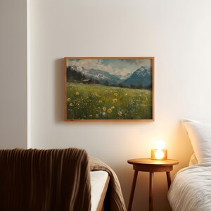 May include: A framed painting of a mountain landscape with a field of yellow wildflowers in the foreground. The painting is hanging on a white wall above a wooden nightstand with a lamp.
