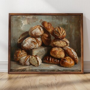 May include: A framed painting depicting a still life of freshly baked bread loaves in various shapes and sizes. The bread is arranged in a pile on a wooden surface, with some loaves spilling over the edge. The painting is set against a neutral background, with soft lighting highlighting the texture of the bread.