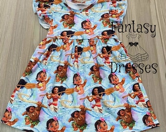 May include: A blue and white dress with a pattern of cartoon characters from the movie Moana. The dress has short sleeves with ruffles and a round neckline. The text "Fantasy Dresses" is visible in the upper right corner of the image.