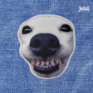 Könnte beinhalten: Ein Aufnäher mit einem weißen Hundegesicht mit schwarzer Nase und sichtbaren Zähnen. Der Aufnäher hat einen weißen Rand und ist vor einem blauen Jeanshintergrund platziert. Der Markenname "Joviall" befindet sich in der oberen rechten Ecke.