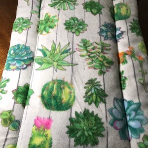 May include: A white pet bed with a gray and white striped pattern and a green succulent print. The bed has a removable pillow.