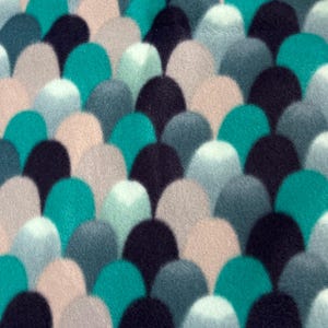 May include: Close-up of a fabric with a repeating pattern of rounded shapes. The shapes are in shades of teal, navy, gray, and beige, creating a textured, layered effect. The design resembles overlapping scales or petals.