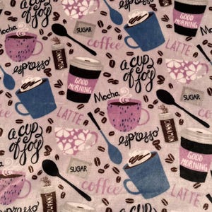 May include: A light purple fabric with a coffee-themed pattern. The design includes coffee cups, spoons, coffee beans, and text such as "espresso", "latte", and "good morning". The words "a cup of joy" are also present.