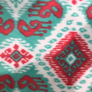May include: A close-up of a fabric with a white background and a repeating pattern of red and teal diamonds.
