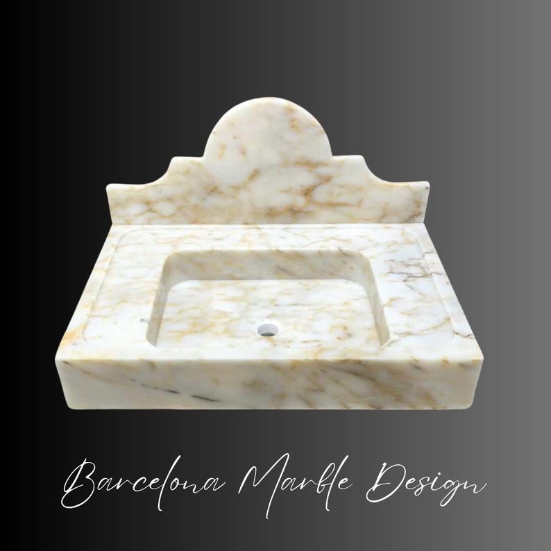 Puede incluir: Un lavabo rectangular de m&aacute;rmol con un protector contra salpicaduras incorporado y una parte superior semicircular. La pila del lavabo es rectangular con un orificio de drenaje. El m&aacute;rmol tiene un patr&oacute;n veteado crema y marr&oacute;n. El texto "Barcelona Marble Design" est&aacute; en la parte inferior.