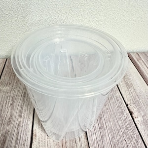 May include: A set of four clear plastic nesting bowls. The bowls are stacked on top of each other, with the largest bowl on the bottom and the smallest bowl on top.