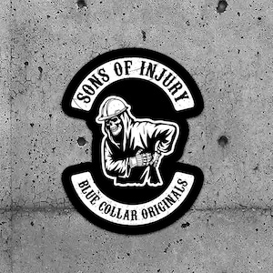 May include: Two black and white stickers with the text "SONS OF INJURY" and "BLUE COLLAR ORIGINALS". Each sticker features a skeleton wearing a hard hat and holding a tool. The stickers are on a grey concrete background.