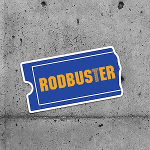 Peut inclure: Deux autocollants en forme de billet bleu et blanc avec le mot "RODBUSTER" imprimé en lettres jaunes.
