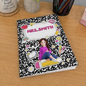 May include: A black and white composition notebook featuring a central label with the text MRS. SMITH. The cover displays a cartoon character in a purple sweater and blue jeans sitting on a yellow pencil, surrounded by colorful icons of flowers, a rainbow, a book, and a red apple.