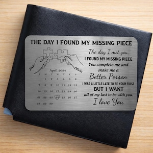 May include: A silver metal wallet card with the text "THE DAY I FOUND MY MISSING PIECE". It features a puzzle piece design, a calendar for April 2024, and the words "I love You". The card is on a black wallet.