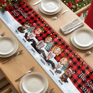 May include: A personalized Christmas table runner with a red and black buffalo plaid pattern. The runner features cartoon illustrations of family members and pets, with names and the year 2025 printed on it. The design includes snowflakes and Christmas trees.
