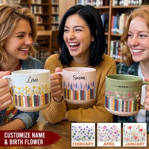 May include: Three ceramic mugs featuring a row of colorful books at the base and floral illustrations above. The mugs are personalized with the names Lisa, Susan, and Mina in black script. Each mug has a speckled finish and a sturdy handle.