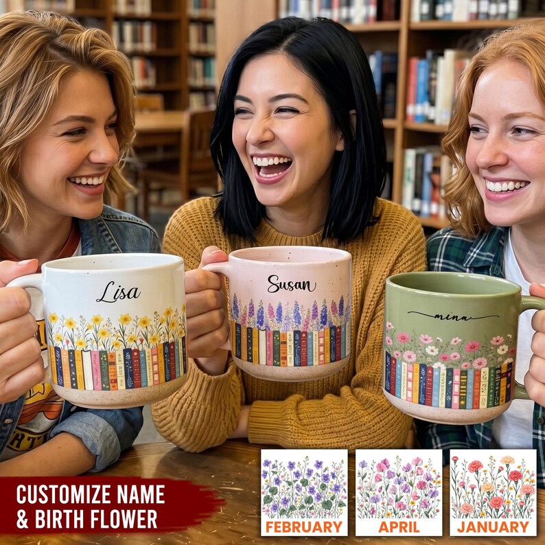May include: Three ceramic mugs featuring a row of colorful books at the base and floral illustrations above. The mugs are personalized with the names Lisa, Susan, and Mina in black script. Each mug has a speckled finish and a sturdy handle.