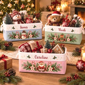 May include: Three rectangular fabric storage baskets with rope handles, personalized with the names James, Noah, and Caroline. Each basket features a white top band with holly accents and a colorful base decorated with Christmas motifs like snowmen, gingerbread figures, candy canes, and pine branches, filled with holiday gifts and plush toys.