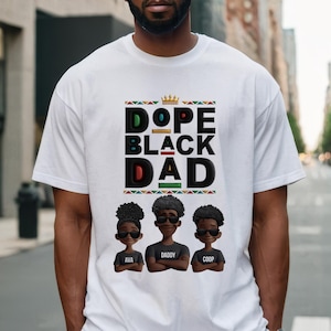 May include: White t-shirt with the text "DOPE BLACK DAD" in black, green, and red. Below the text are three cartoon figures wearing sunglasses. The figures have the names "AVA", "DADDY", and "COOP" printed below them.