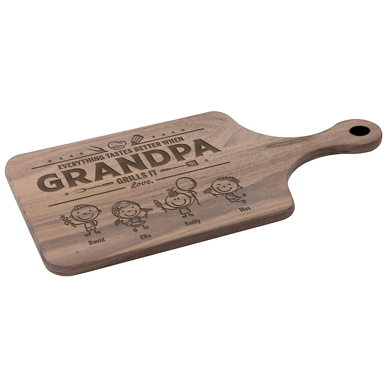 Może przedstawiać: Drewniana deska do krojenia z uchwytem, ​​z wygrawerowanymi słowami "GRANDPA GRILLS IT" oraz imionami David, Ella, Emily i Max. Deska ma ciemne usłojenie drewna i otw&oacute;r w uchwycie do zawieszania.