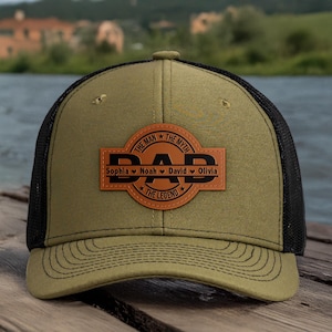 Könnte beinhalten: Olivgrüne und schwarze Trucker-Cap mit einem Lederaufnäher mit dem Schriftzug "DAD" in schwarzen Buchstaben. Der Aufnäher enthält auch die Worte "THE MAN, THE MYTH, THE LEGEND" und die Namen Sophia, Noah, David und Olivia.