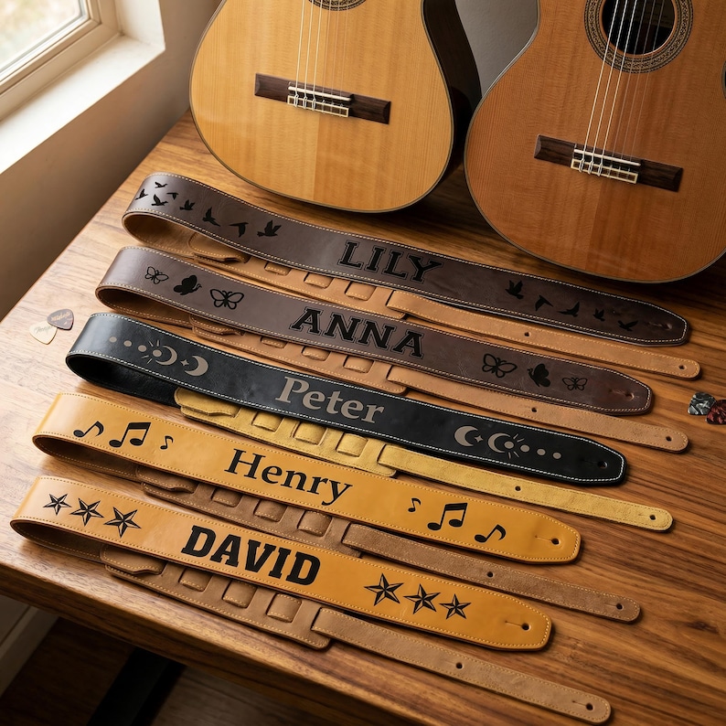 May include: Five leather guitar straps in varying shades of brown and black, each personalized with a name: LILY, ANNA, Peter, Henry, and DAVID. The straps feature engraved designs including birds, butterflies, moon phases, musical notes, and stars.