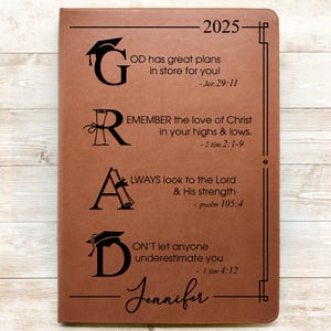 May include: A brown leather journal with the year 2025 and the name Jennifer embossed on the front. The journal has the letters G, R, A, and D with inspirational quotes and bible verses.