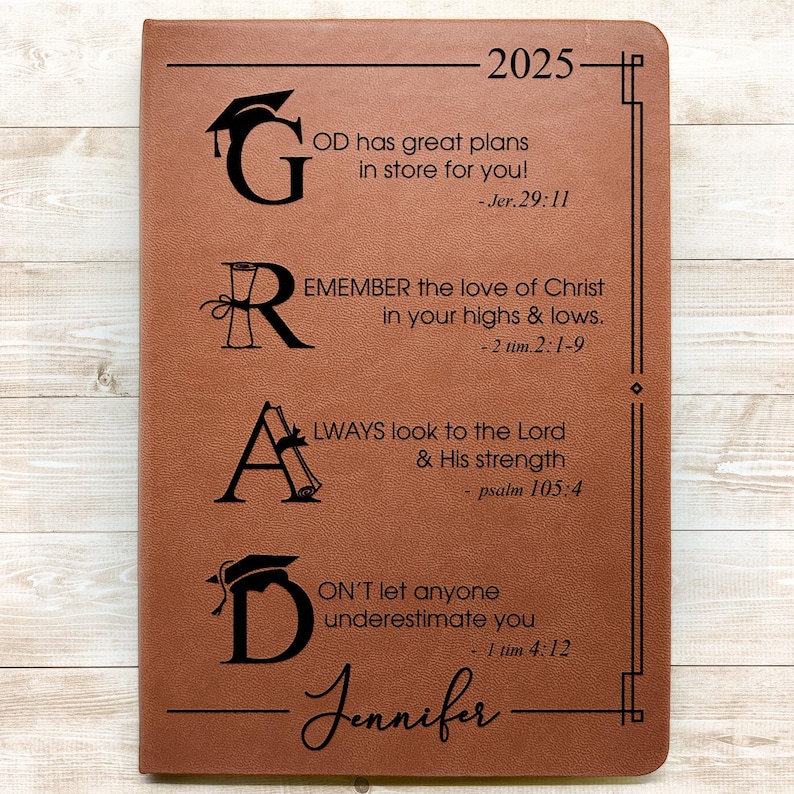 May include: A brown leather journal with the year 2025 and the name Jennifer embossed on the front. The journal has the letters G, R, A, and D with inspirational quotes and bible verses.