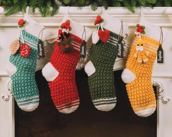 以下が含まれることがあります： 手作りのクリスマスストッキング4つ。ティール、赤、緑、黄色で、それぞれ白い袖口とつま先が付いています。ストッキングはかぎ針編みで、小さなオーナメントと「Margaret」、「Jason」、「Michael」、「Sophia」と書かれたネームタグで飾られています。