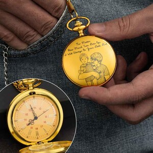 Puede incluir: Un reloj de bolsillo dorado con una cadena, sostenido por una persona. La esfera del reloj es visible, mostrando la hora. La parte posterior del reloj tiene una imagen grabada de una persona sosteniendo a un ni&ntilde;o, con el texto "No Matter How Much Time Goes By I Will Always Be Your Little Girl."
