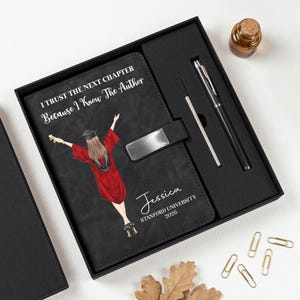 May include: A black gift set featuring a journal, pen, and ink refill. The journal has a graduation-themed illustration and the text "I TRUST THE NEXT CHAPTER Because I Know The Author" and the name "Jessica" and "STANFORD UNIVERSITY 2026".