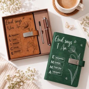 May include: A tan journal in a gift box with a pen and a green journal. The tan journal features the text God says You Are, the name ALICE, and floral line art. The green journal features the text God says I Am, the name EMMA, and floral line art.