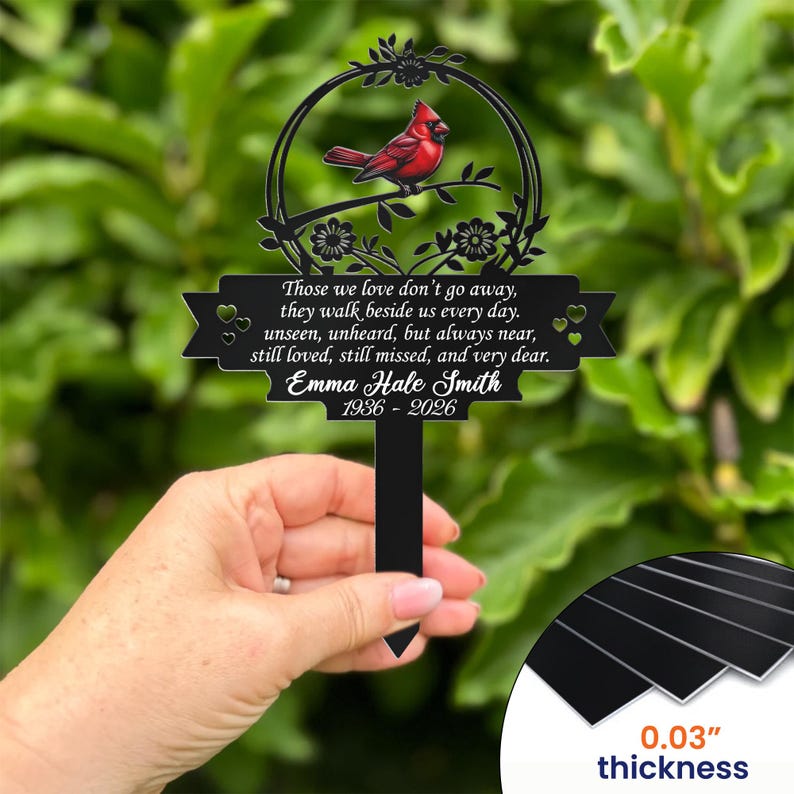 May include: Black metal memorial garden stake featuring a red cardinal perched on a branch within a circular frame. The stake includes a banner with an inscription and the name "Emma Hale Smith" with dates 1936-2026. The stake is 0.03" thick.