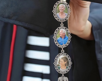 May include: A graduation tassel with three oval photo charms. The charms are silver-toned with ornate frames, each holding a photograph. A small gold charm with the year "2026" is at the top, and a pair of angel wings dangles at the bottom.
