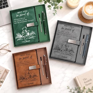 Könnte beinhalten: Drei rechteckige Geschenksets, die jeweils ein Notizbuch mit Metallverschluss und einen passenden Stift enthalten. Die Notizbücher sind grün, grau und braun und zeigen eine Winnie Puuh-Illustration, den Text "MAY YOU be proud of THE WORK YOU DO THE PERSON YOU ARE AND THE DIFFERENCE YOU MAKE" sowie einen personalisierten Namen.