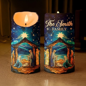 May include: Two cylindrical LED candles with a religious theme. The candles feature a stained-glass design depicting a nativity scene under a starry night sky. One candle has the text "The Smith Family". The candles have a warm, flickering glow.
