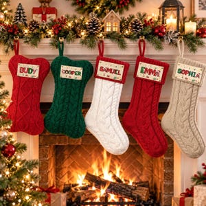 May include: Five cable-knit Christmas stockings in red, green, white, red, and beige, each featuring a rectangular wooden name tag. The tags are printed with the names BUDY, COOPER, SAMUEL, EMMA, and SOPHIA, decorated with small festive holiday icons.