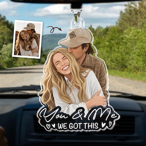 Puede incluir: Un adorno de coche de acr&iacute;lico transparente con una ilustraci&oacute;n personalizada de una pareja basada en una peque&ntilde;a foto insertada. La ilustraci&oacute;n muestra a una persona con cabello rubio largo abrazando a una persona con gorra de b&eacute;isbol beige. Texto: You & Me WE GOT THIS.