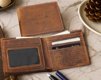 May include: A brown leather wallet with a personalized design. The wallet is open, revealing card slots and a clear ID window. The exterior features the initials "m & k" with a heart and the date "06.17.25". The interior has a printed message.