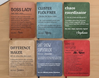 May include: Six notebooks with definitions, including "BOSS LADY," "CLUSTER FUCK FIXER," and "CHAOS COORDINATOR." Each notebook has a different color and a definition printed on the cover. The notebooks are arranged on a light-colored surface.