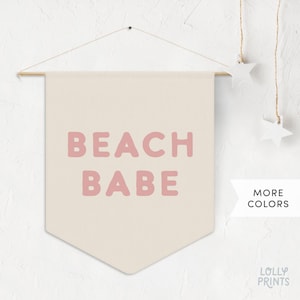 May include: A beige canvas wall banner with the text "Beach Babe" in pink lettering.
