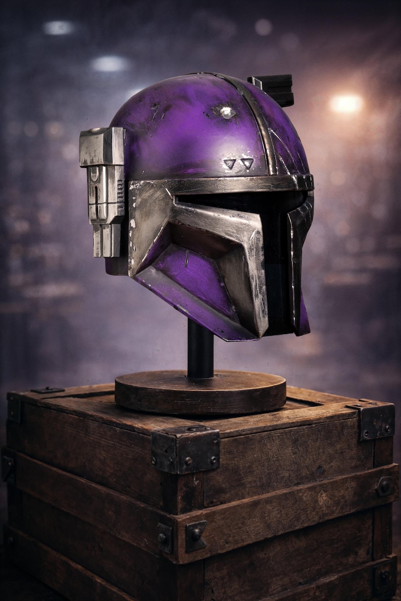 Peut inclure: Casque futuriste violet et argent&eacute;, probablement un accessoire ou un objet de collection, expos&eacute; sur un socle en bois pos&eacute; sur une bo&icirc;te en bois. Le casque pr&eacute;sente un design angulaire et une visi&egrave;re. La palette de couleurs comprend des nuances de violet et d'argent.