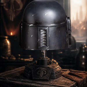 Peut inclure: R&eacute;plique de casque Mandalorien noir, pr&eacute;sent&eacute;e sur un socle. Le casque pr&eacute;sente un aspect vieilli avec des signes d'usure. Le socle porte un symbole et est pos&eacute; sur une surface sombre et textur&eacute;e, sugg&eacute;rant un objet de collection.
