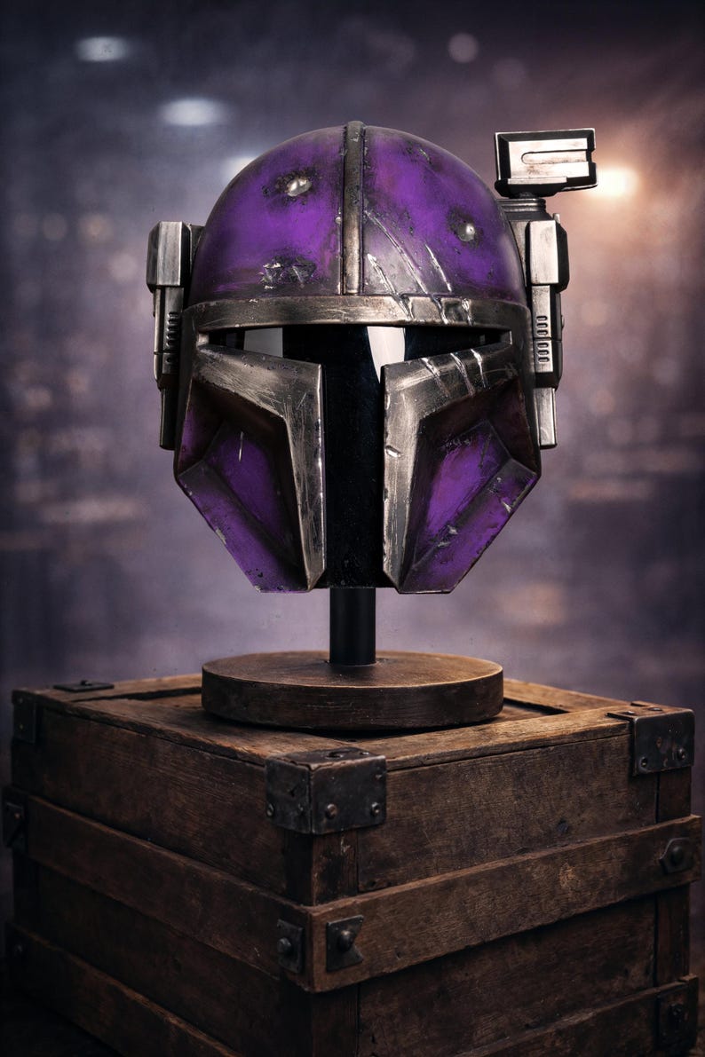 Peut inclure: Casque violet et argent&eacute;, probablement pour le cosplay ou l'affichage, mont&eacute; sur un support en bois au-dessus d'une bo&icirc;te en bois. Le casque a un aspect vieilli avec des signes d'usure. L'arri&egrave;re-plan est flou, sugg&eacute;rant un cadre de studio.